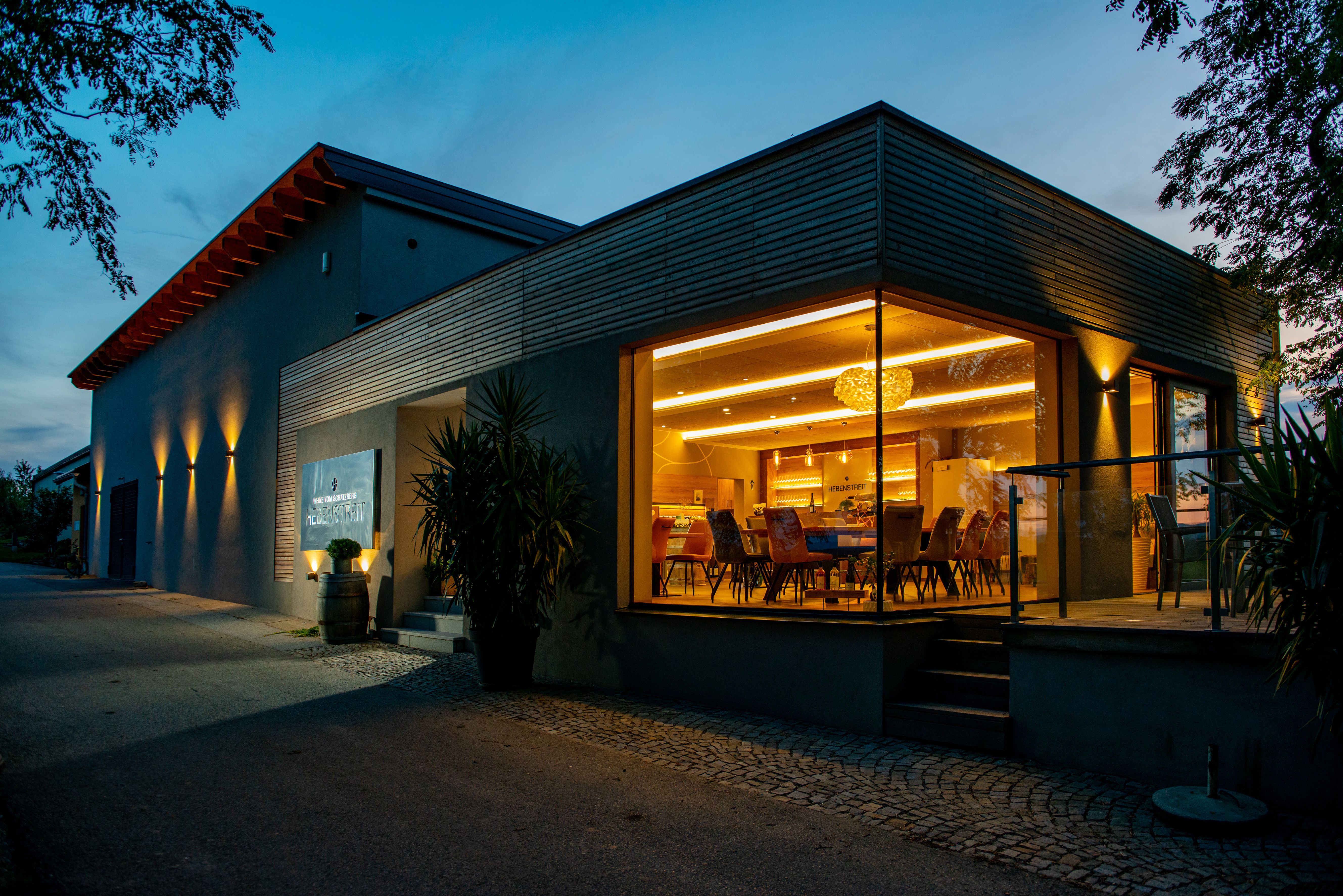 Modernes Gebäude mit Glasfront und Innenbeleuchtung bei Dämmerung.