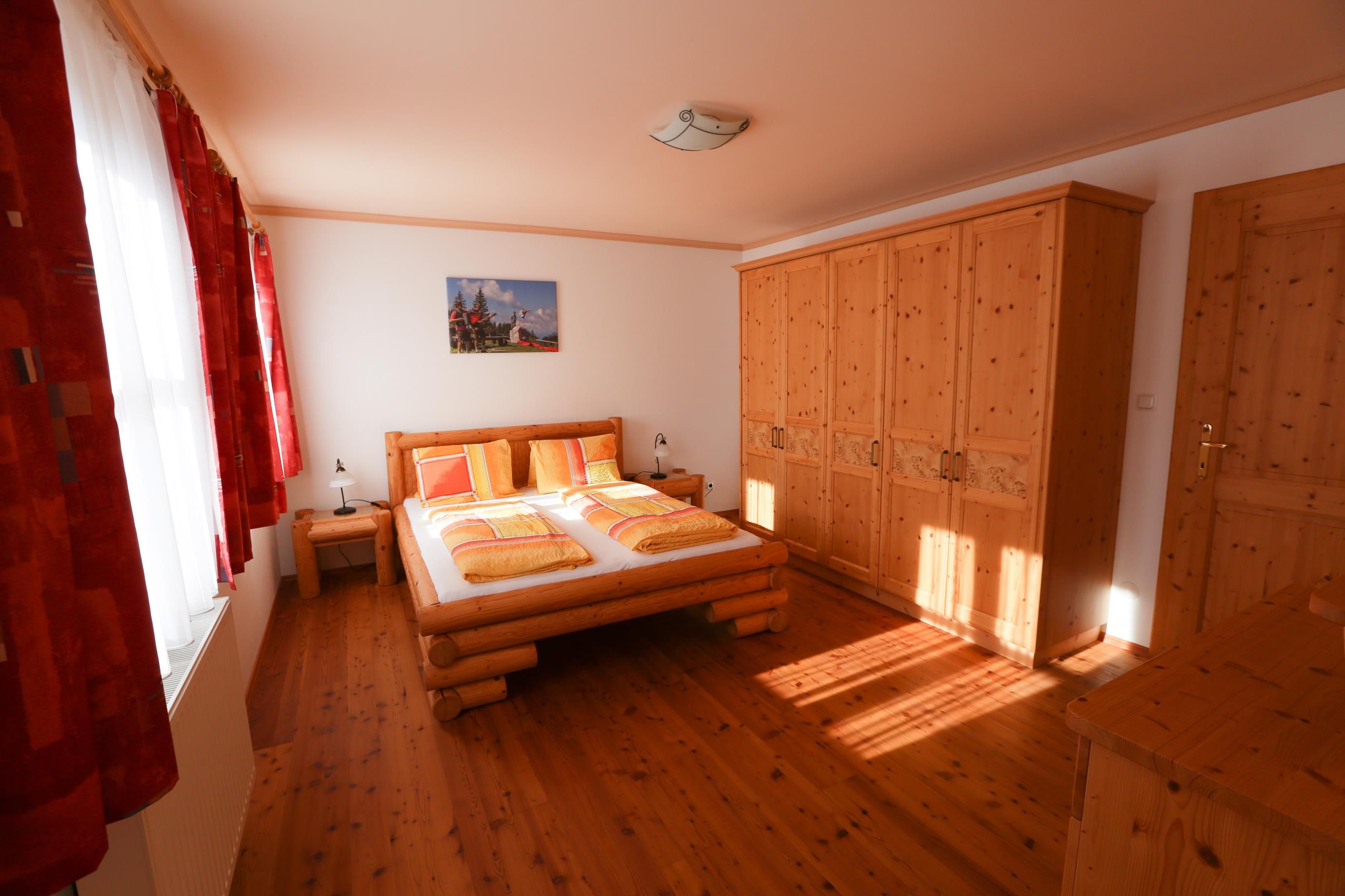 Schlafzimmer mit Holzmöbeln, Doppelbett und Kleiderschrank.