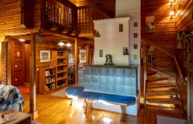 Gem&uuml;tliches Wohnzimmer mit Kachelofen, Holzw&auml;nden und Treppe.