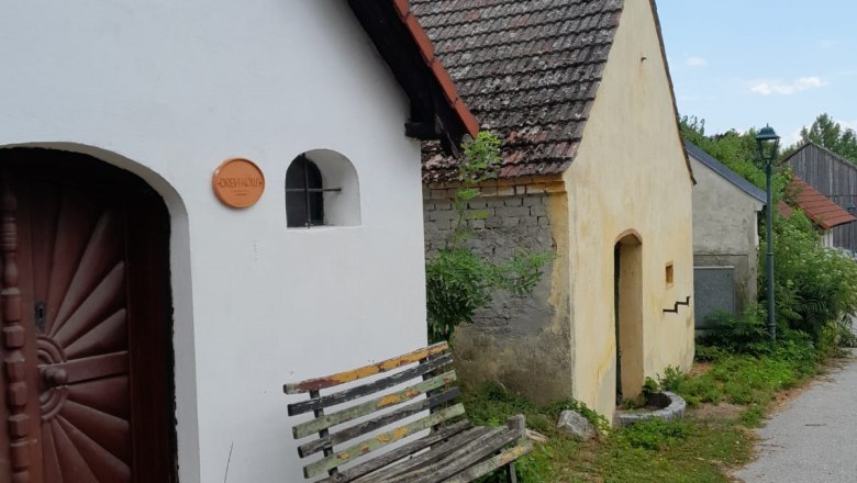 Eine Reihe von kleinen, traditionellen Geb&auml;uden mit Ziegeld&auml;chern und einer Holzbank davor.