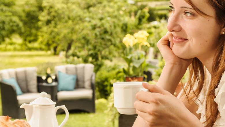 Frau genie&szlig;t Kaffee im Freien mit Blick auf Weinberge.