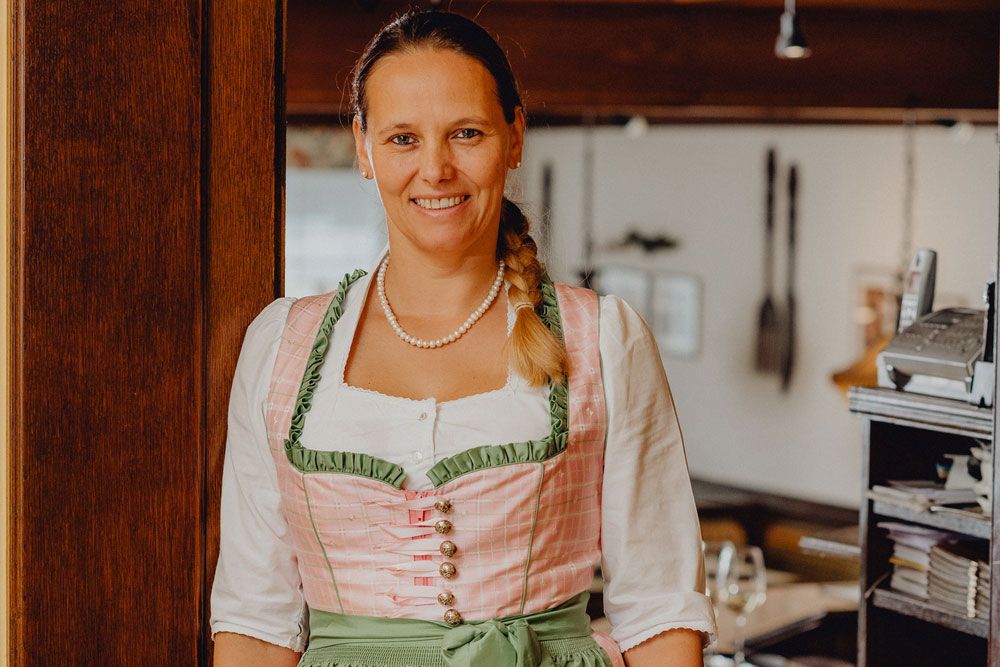 Frau in traditioneller Tracht lächelt in einem Restaurant.