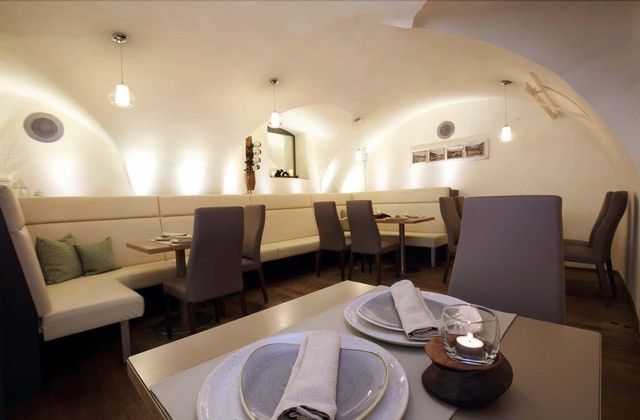 Eleganter Gastraum mit gewölbter Decke, modernen Möbeln und gedecktem Tisch.