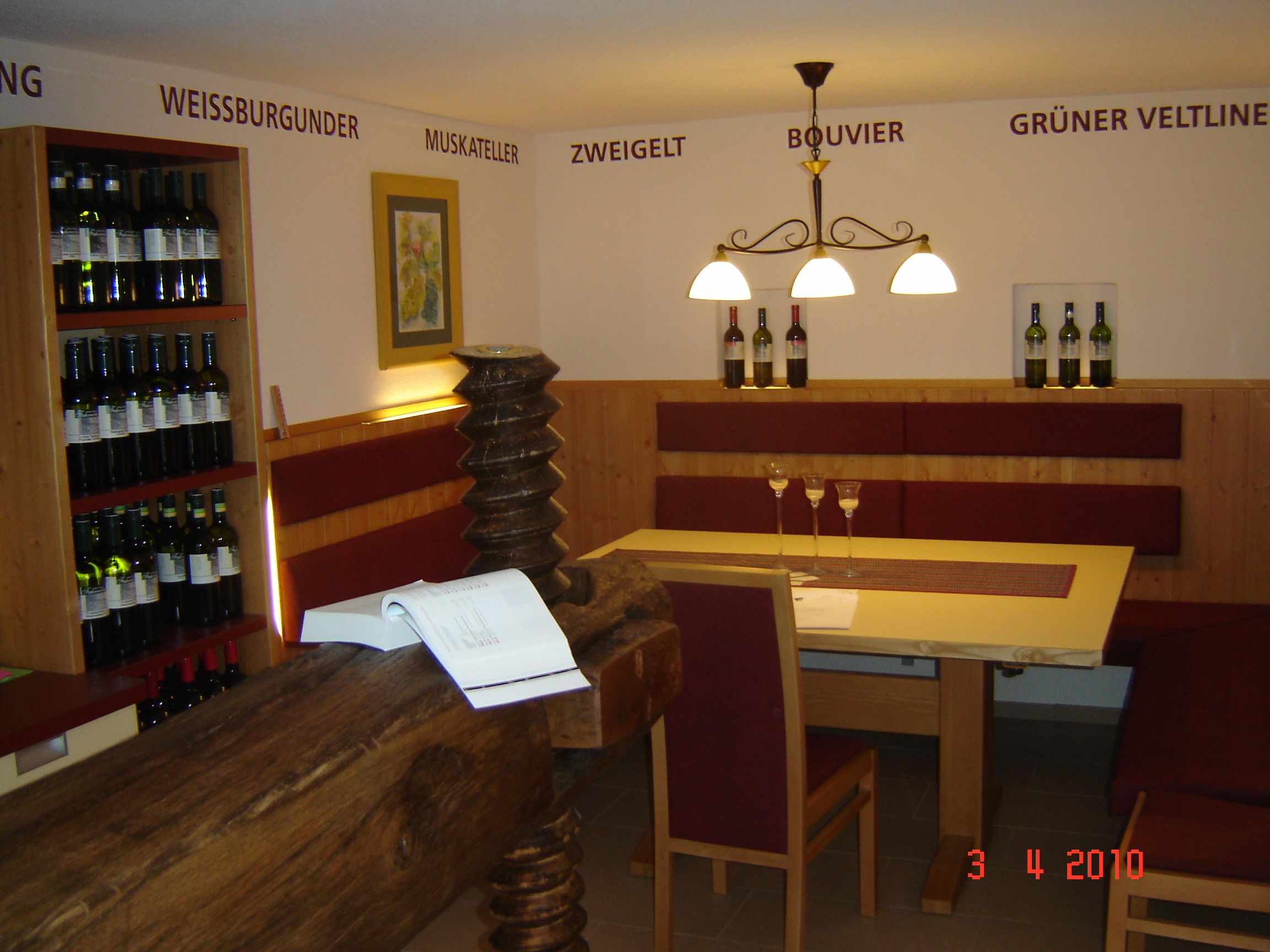 Innenansicht eines Weinguts mit Tisch, Stühlen und Weinregalen.