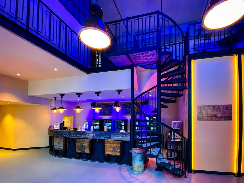 Innenansicht einer Bar mit Wendeltreppe und blauer Beleuchtung.