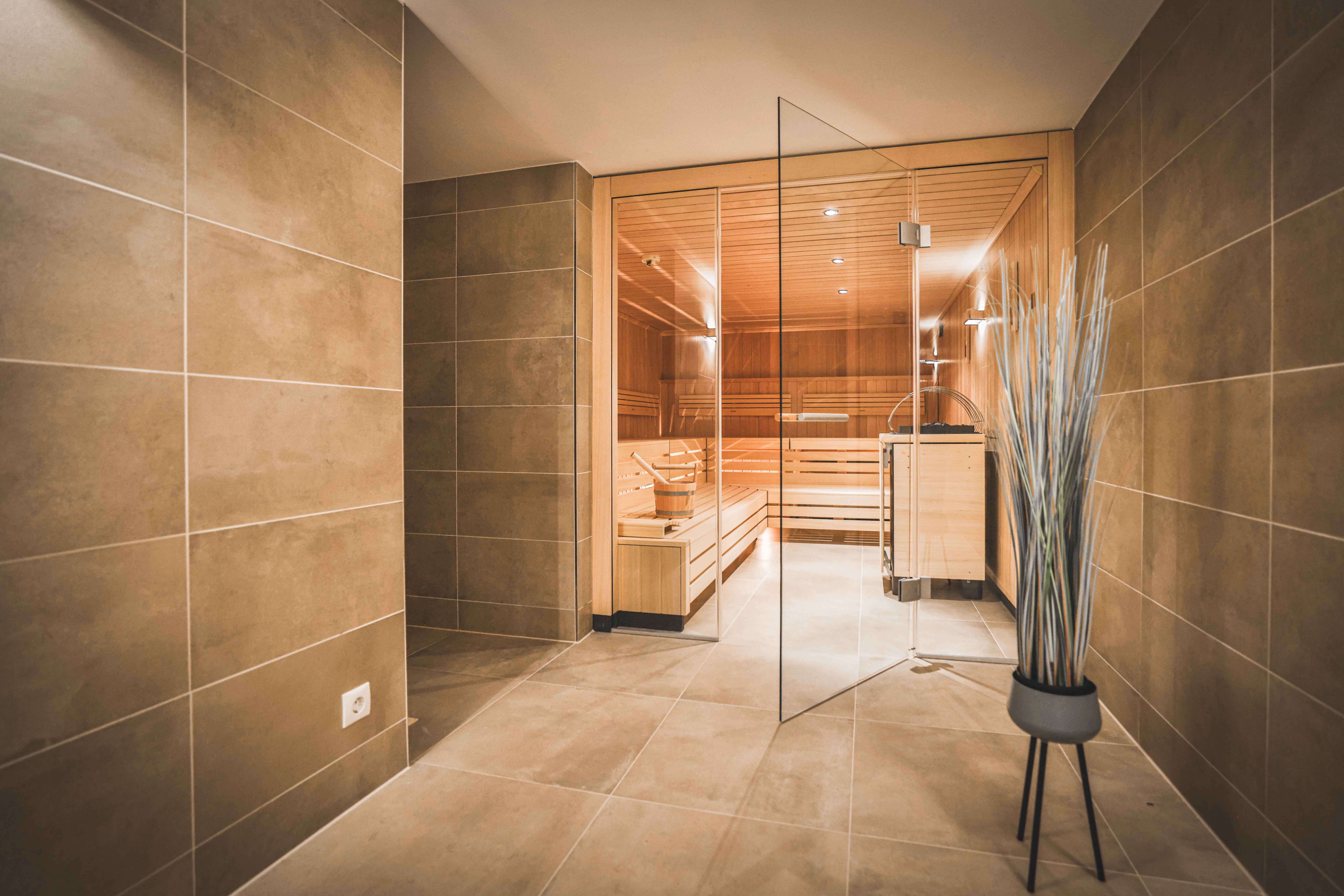 Moderner Saunabereich mit Glaswand und Holzbänken.