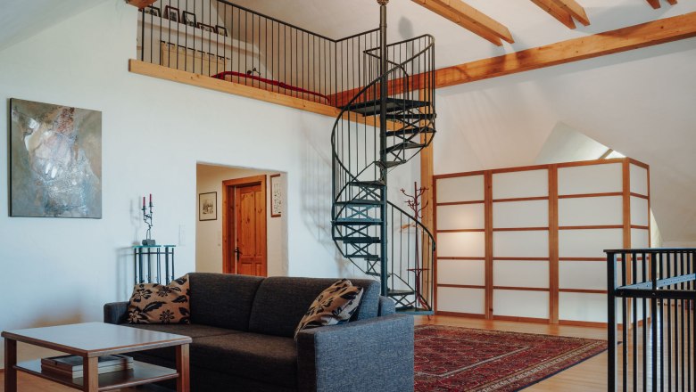 Wendeltreppe hinauf zum Schlafbereich, im Vordergrund gem&uuml;tliche Couch