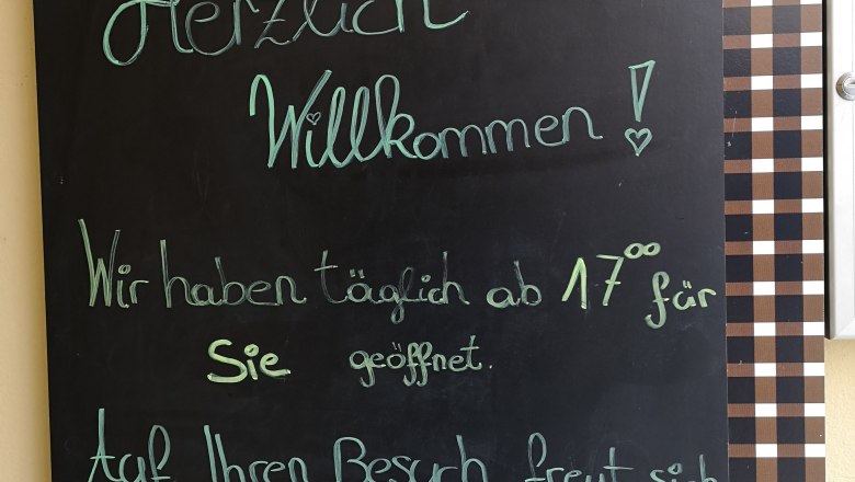 Tafel mit Begrüßungstext vor einer Weinbar namens Kalmuck.