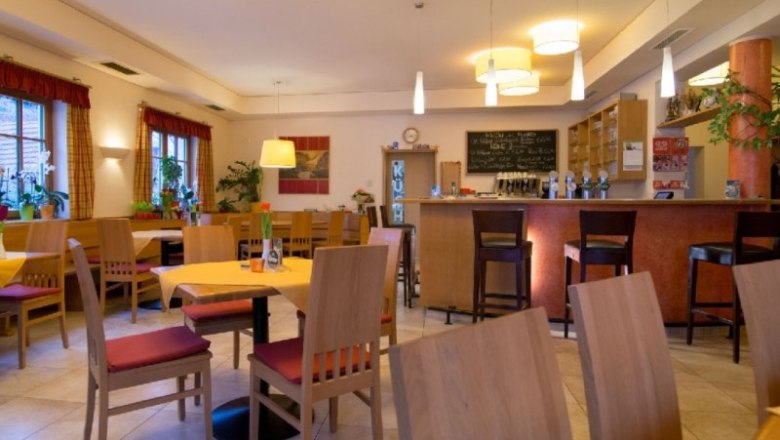 Innenansicht eines gemütlichen Restaurants mit Holzmöbeln und Bar.