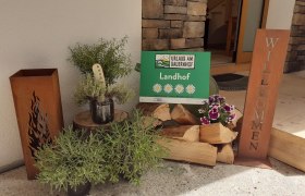 Eingangsbereich mit Holzscheiten und einem Willkommensschild.