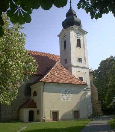 Pfarrkirche Zwentendorf mit Turm und Uhr, umgeben von B&auml;umen.