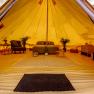 Innenansicht eines luxuri&ouml;sen Glamping-Zeltes mit Bett, Pflanzen und M&ouml;beln.