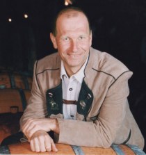 Ein Mann in traditioneller Kleidung lehnt an einem Weinfass.