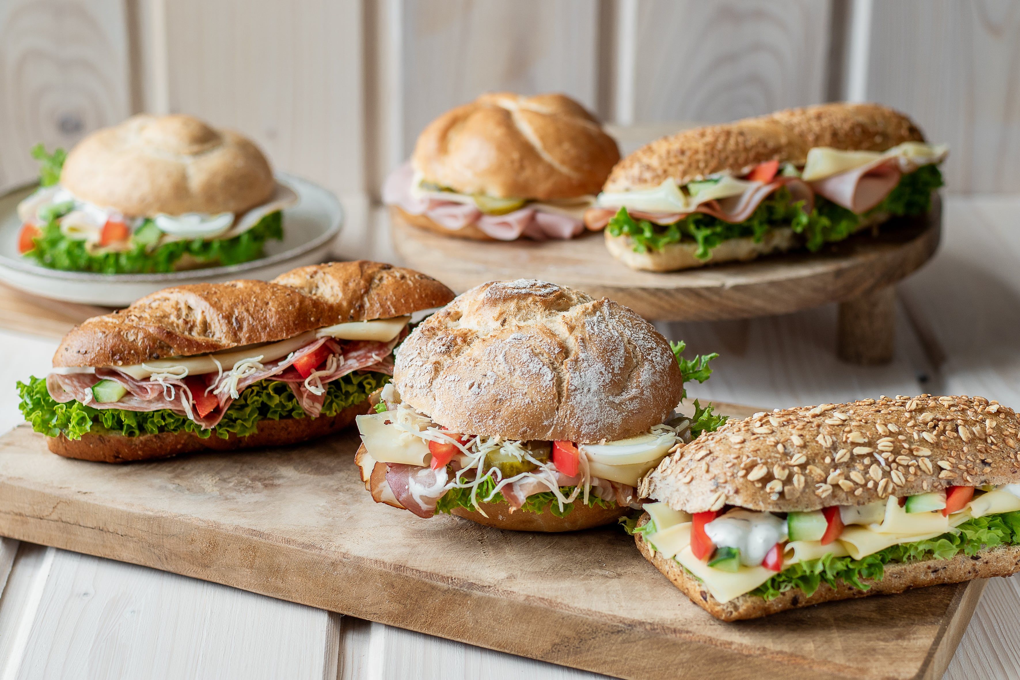 Verschiedene belegte Brötchen auf Holzbrett arrangiert.