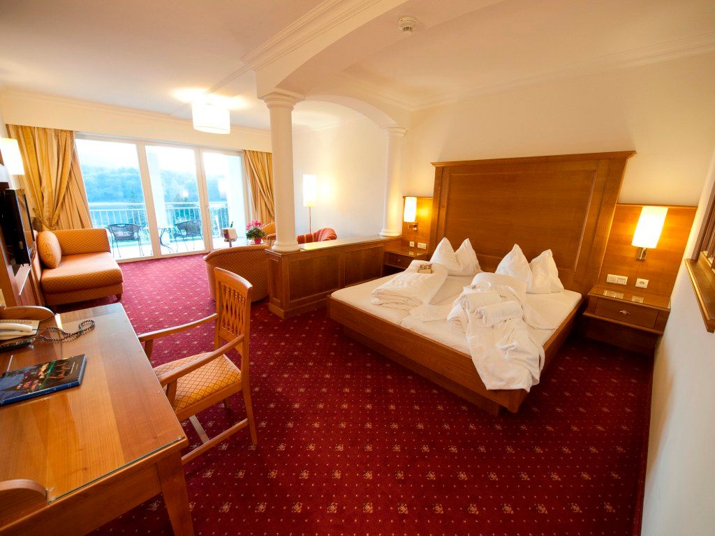 Hotelzimmer mit Doppelbett, Schreibtisch und Balkon mit Ausblick.