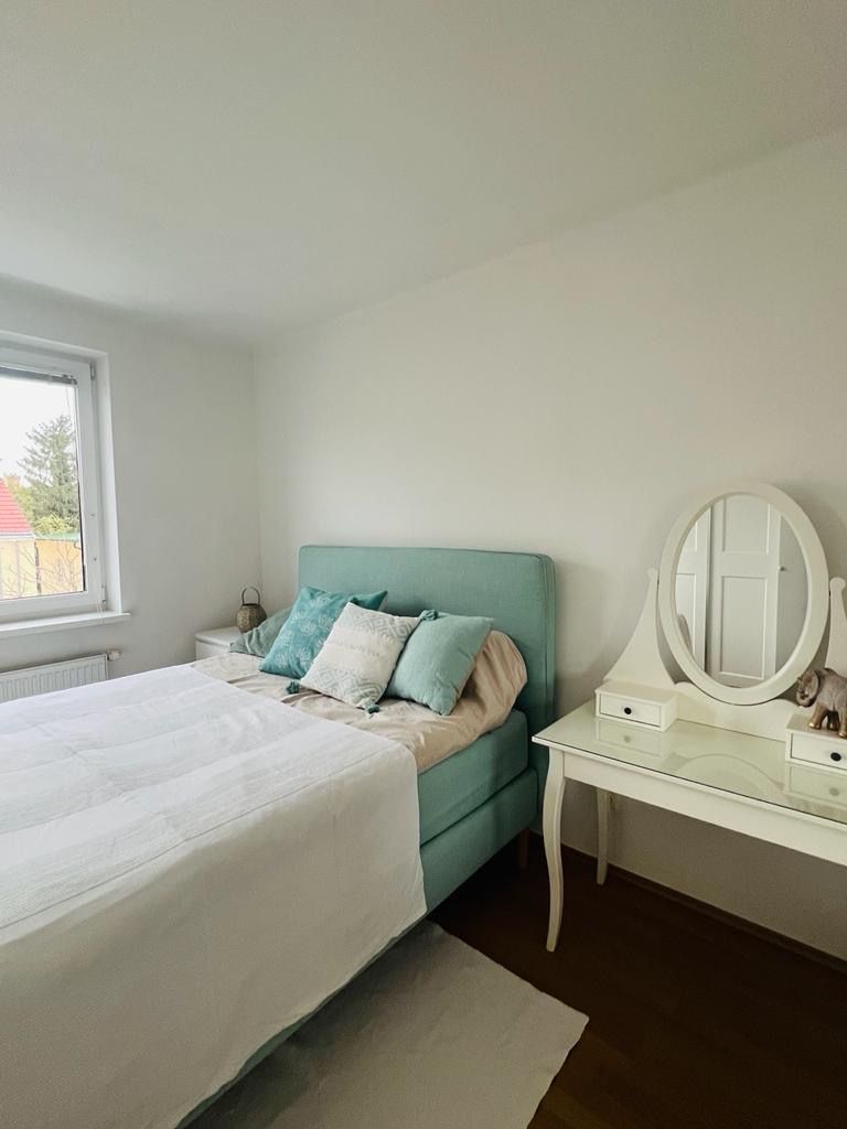Schlafzimmer mit einem Bett, Kissen und einem Schminktisch mit Spiegel.