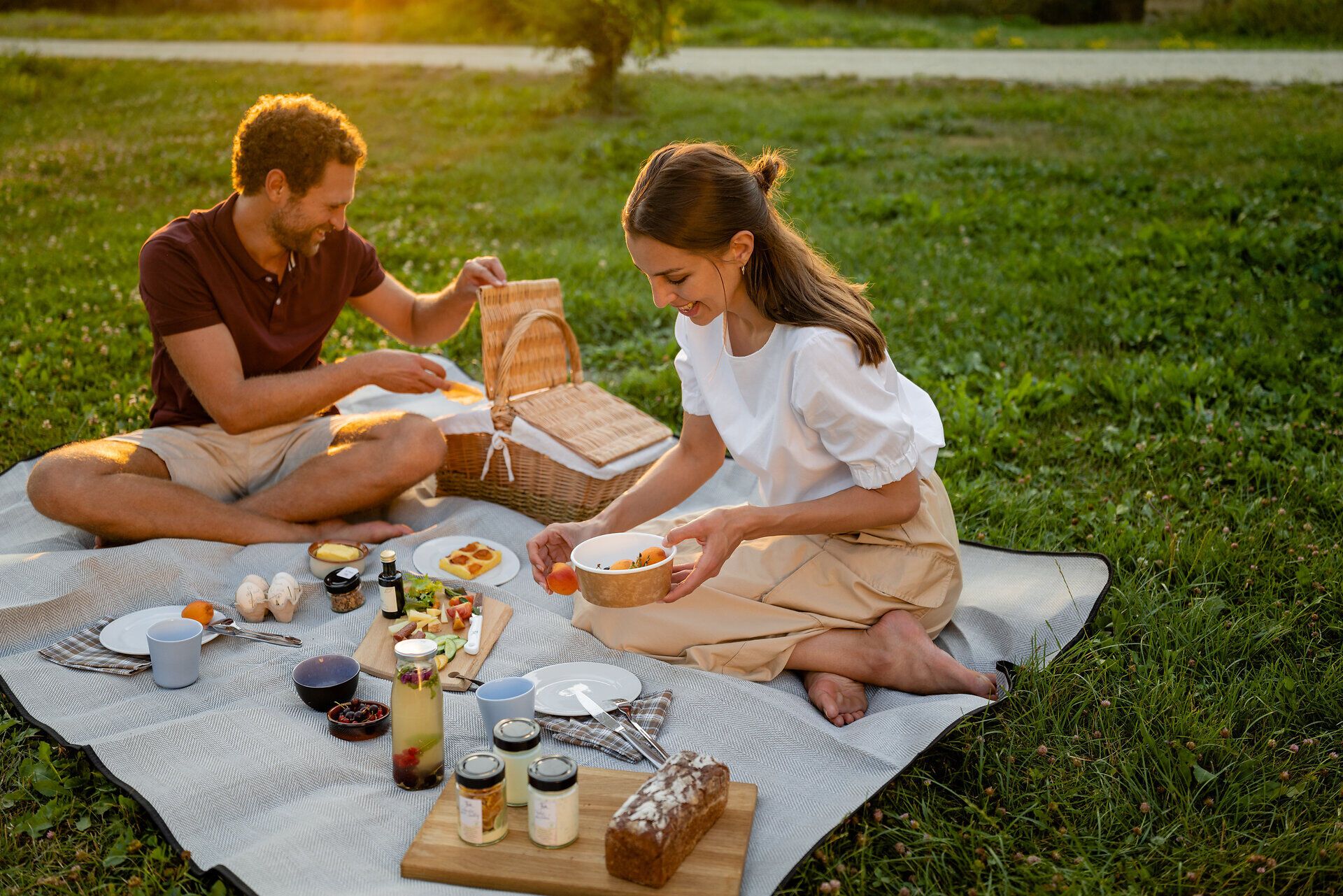 Ein romantisches Picknick im Grünen lädt dazu ein, die warmen Sonnenstrahlen und die frische Luft zu genießen. Die liebevoll angerichteten Speisen und die entspannte Atmosphäre schaffen einen perfekten Moment der Zweisamkeit. Umgeben von der Natur wird jeder Bissen zu einem Genuss.