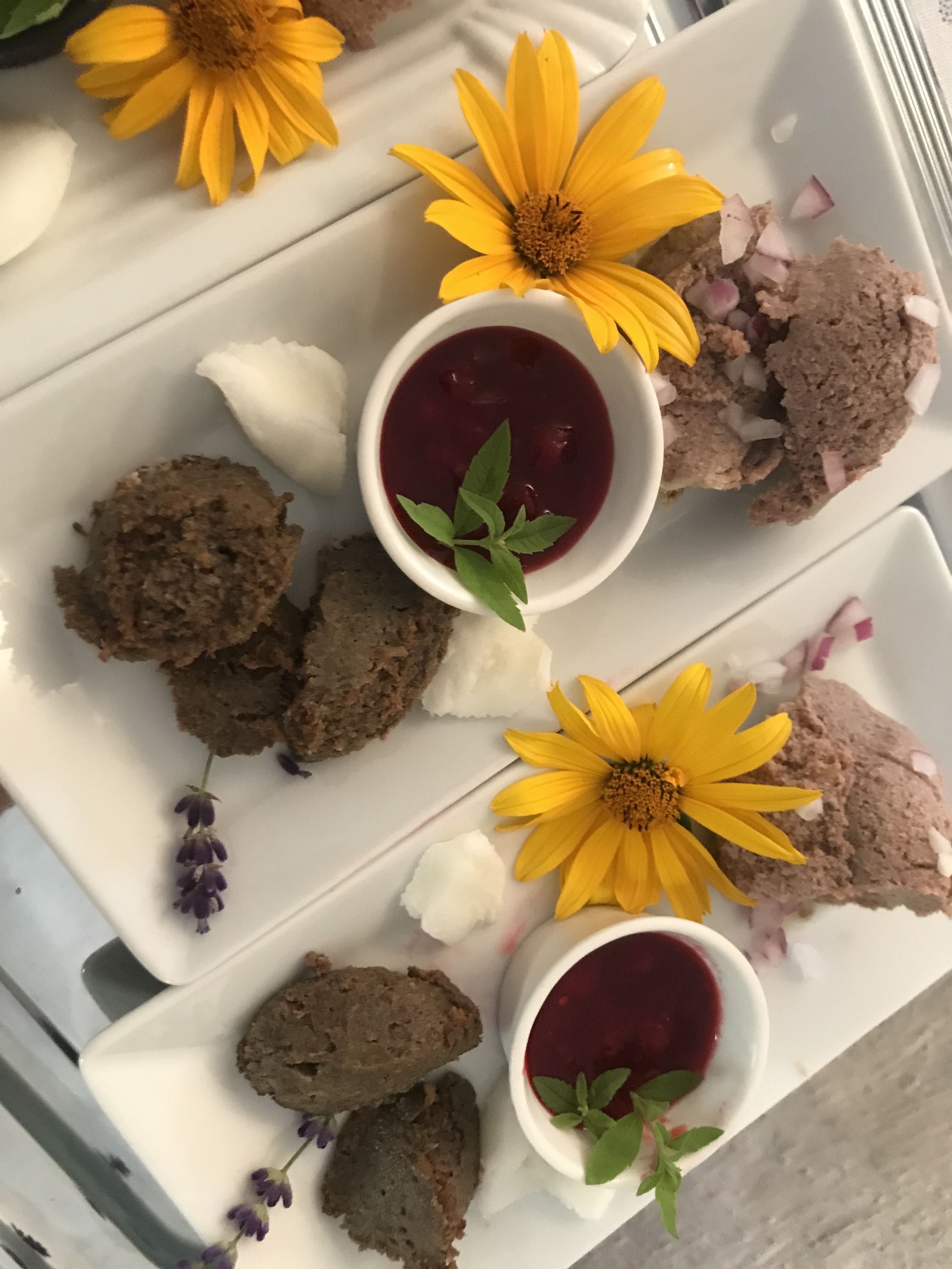 Platten mit Aufstrichen, gelben Blumen und roten Soßen in kleinen Schalen.