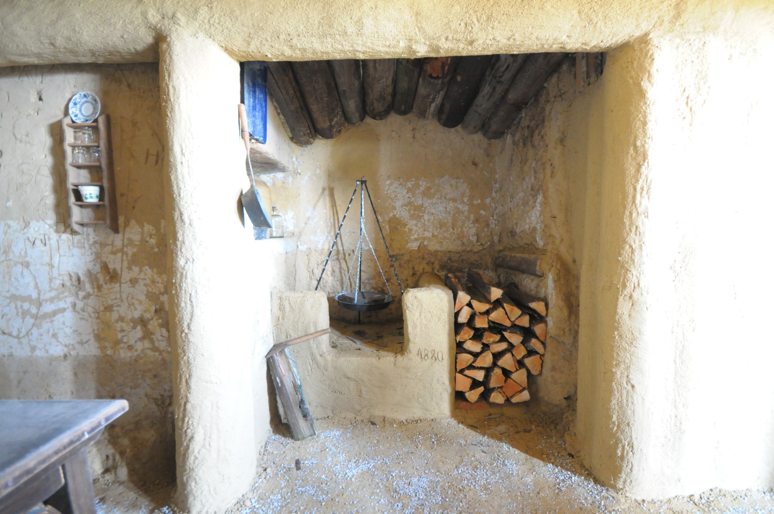 Innenansicht eines rustikalen Raumes mit Kamin und Holzstapel.