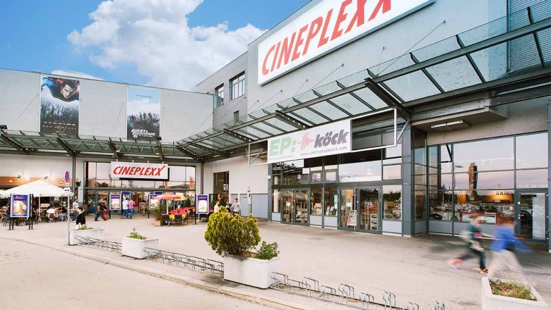 Eingang des Cineplexx Kinos in Wiener Neustadt mit Glasdach und Werbeplakaten.