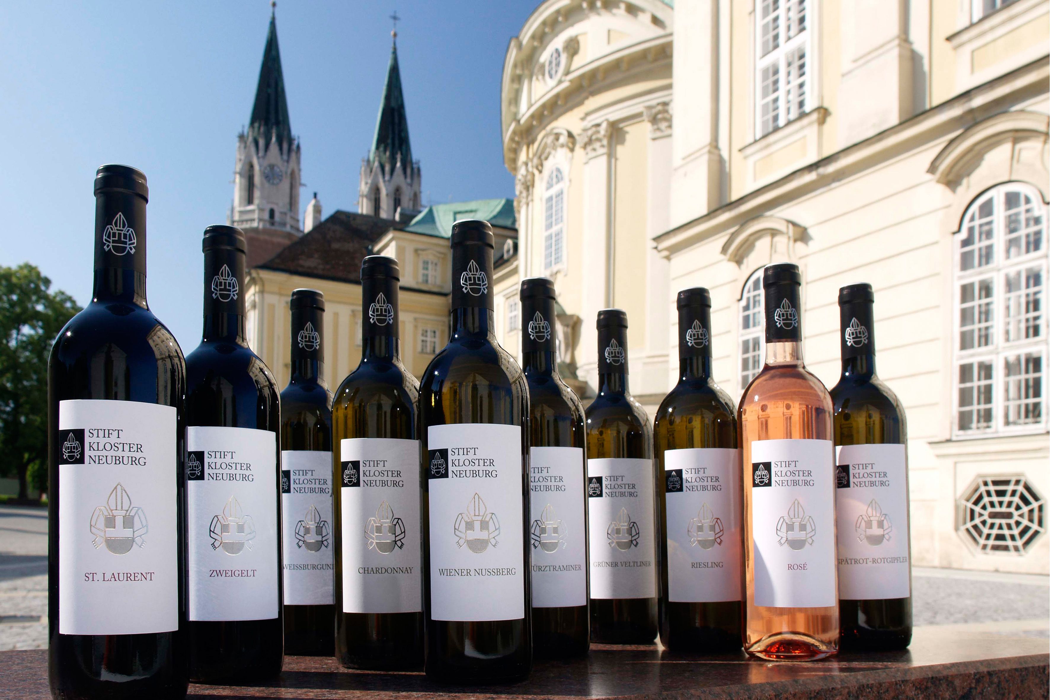 Weinflaschen des Stift Klosterneuburg vor einem historischen Gebäude.