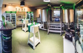 Innenansicht einer kleinen Brauerei mit Edelstahlkesseln und K&uuml;hlschr&auml;nken voller Getr&auml;nke.