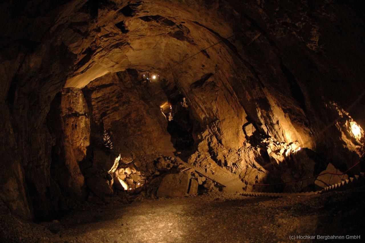Innenansicht einer beleuchteten Höhle mit steinigen Wänden und einem schmalen Pfad.
