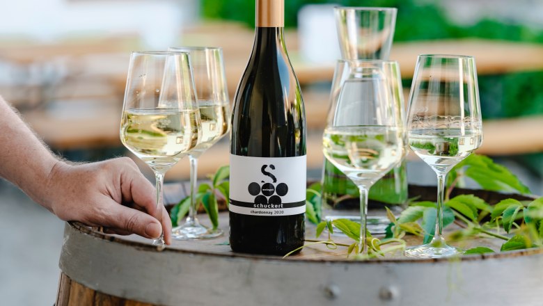 Weinflasche und Gl&auml;ser auf einem Weinfass im Freien.