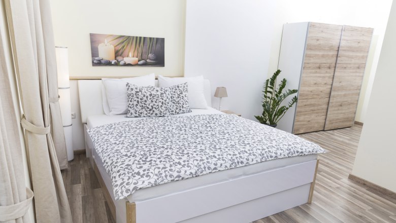 Modernes Schlafzimmer mit Doppelbett, Pflanzen und Schrank.