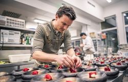 Chefkoch Peter Pichler steht in seiner Küche vom Hotel Molzbachhof. Vor ihm stehen viele angerichtete Teller.