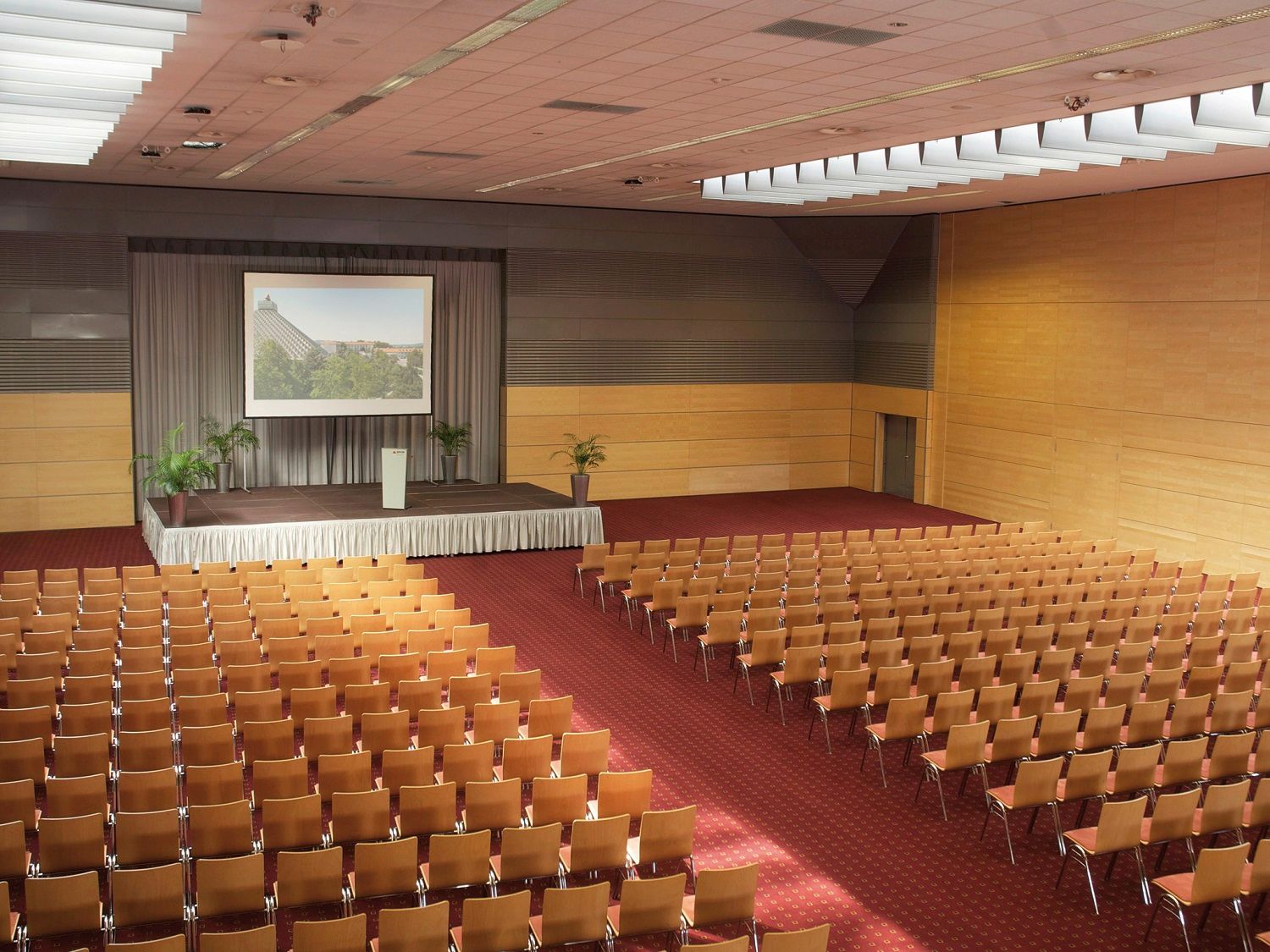 Großer Konferenzsaal mit Bühne und Stuhlreihen.