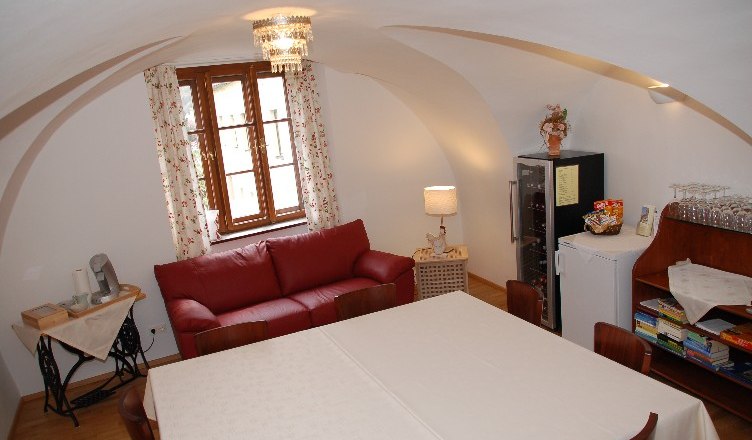 Gem&uuml;tlicher Aufenthaltsraum mit rotem Sofa, Tisch, K&uuml;hlschrank und Spielen.