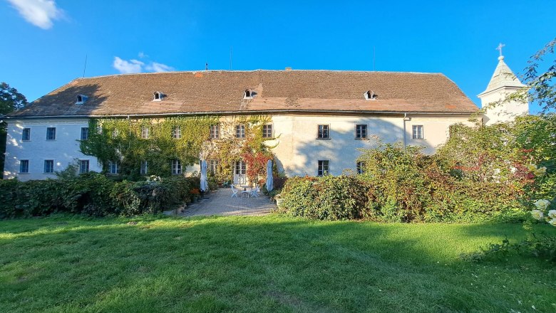 Schloss Poysbrunn mit bewachsener Fassade und Garten.