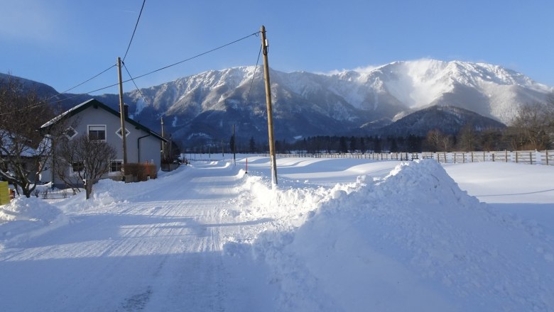 Ferienwohnung Schneebergblick, © Familie Zwinz Verschneite Landschaft mit einem Haus und Bergen im Hintergrund.