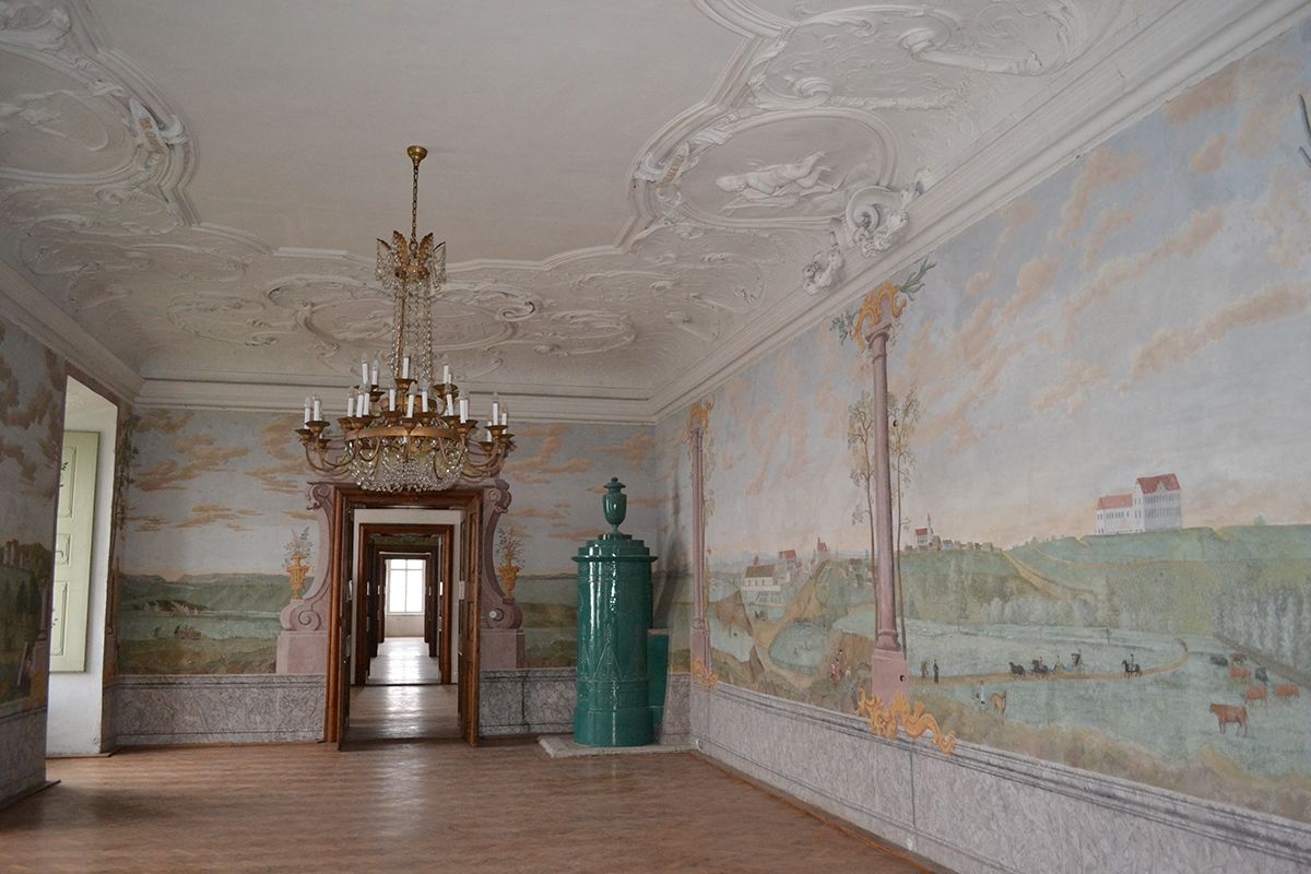 Eleganter Raum im Schloss Stetteldorf mit Wandmalereien und einem Kronleuchter.