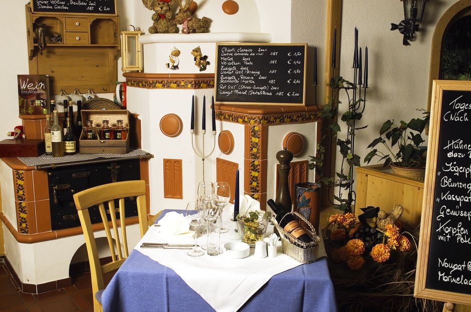 Gemütliche Kaminstube mit gedecktem Tisch, Weinkarten und Dekorationen.