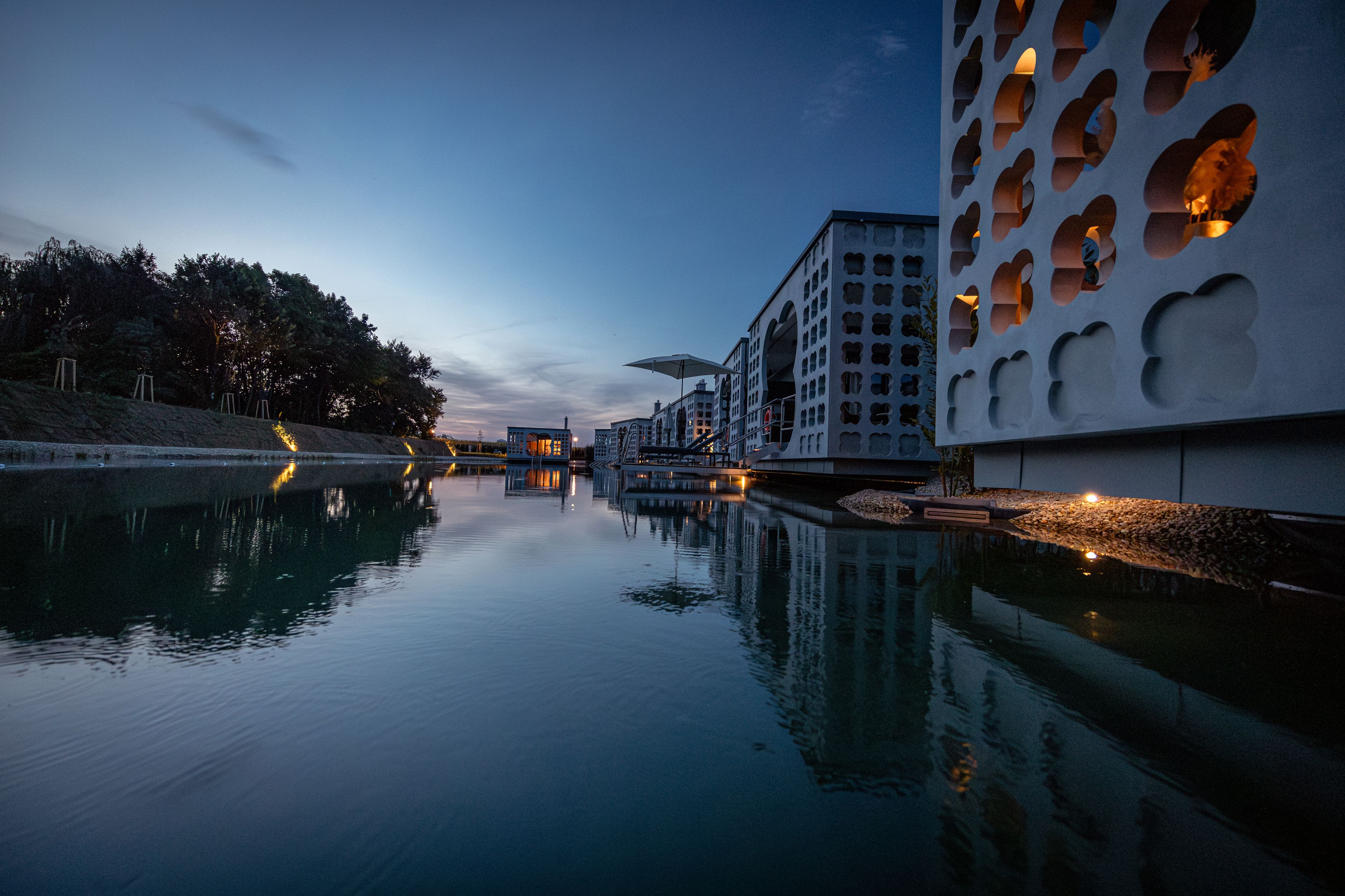 Moderne Gebäude mit Wasserreflexionen bei Dämmerung.