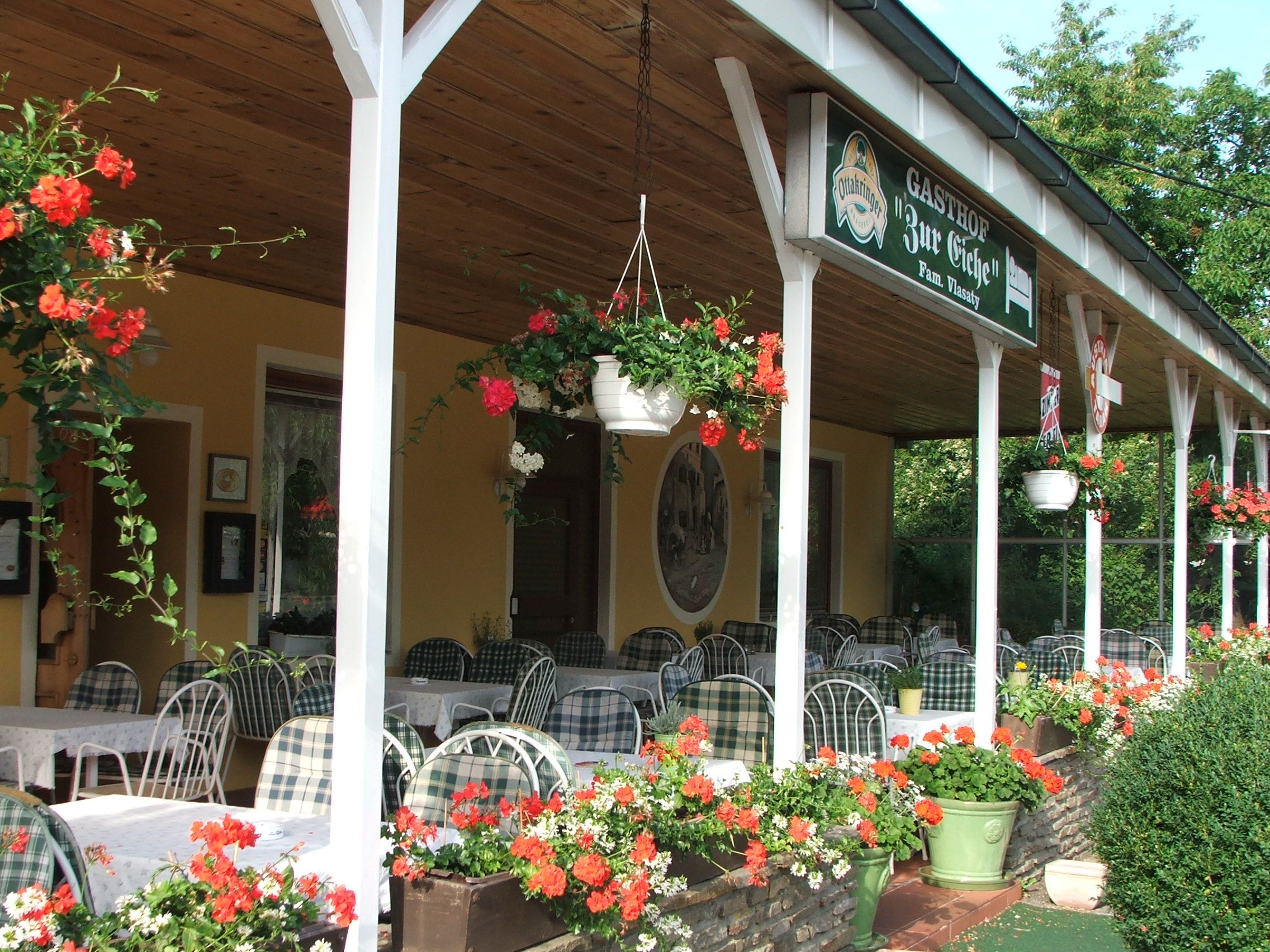 Außenbereich eines Gasthofs mit Tischen und Blumen.
