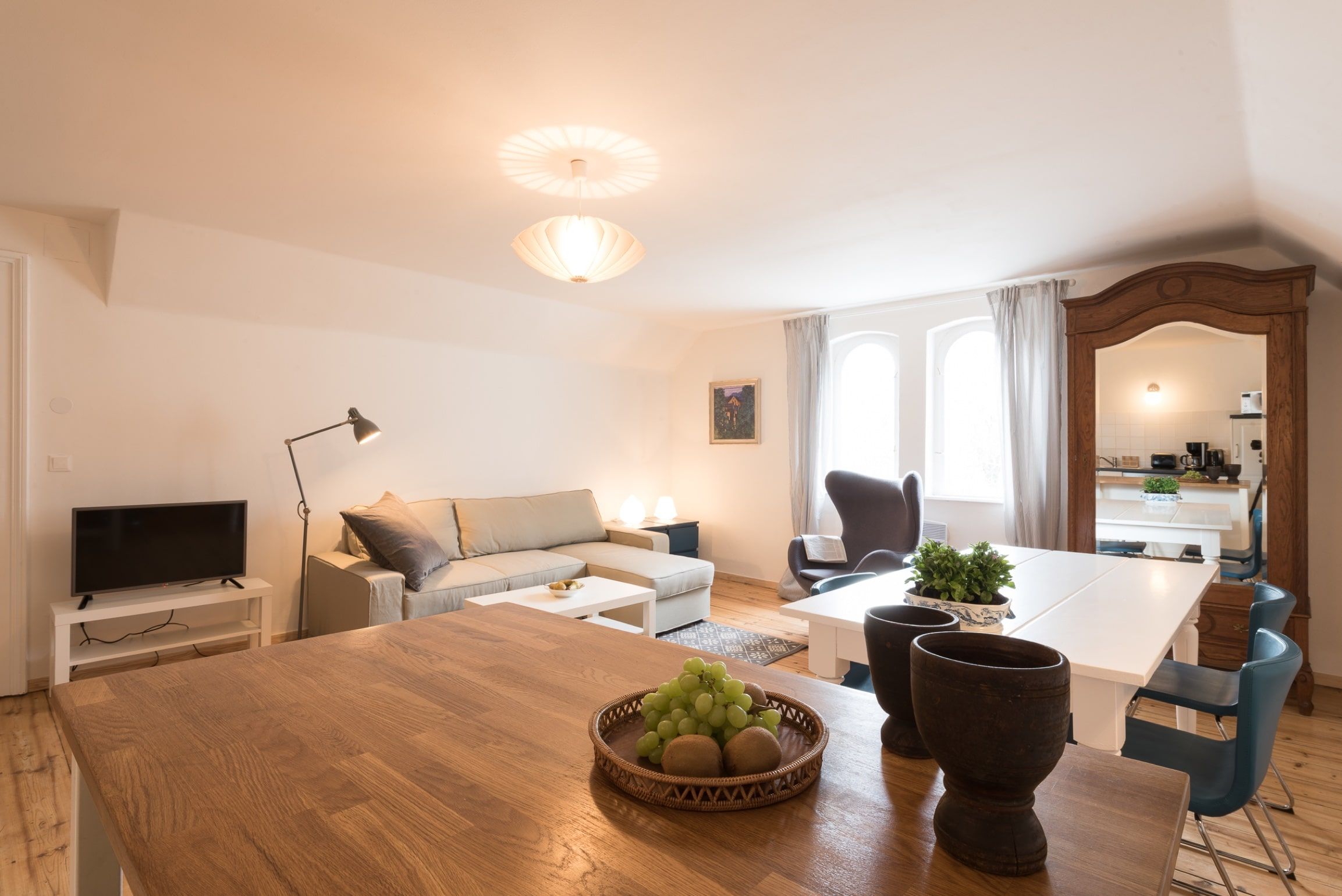 Modernes Wohnzimmer mit Sofa, Esstisch und Spiegel.