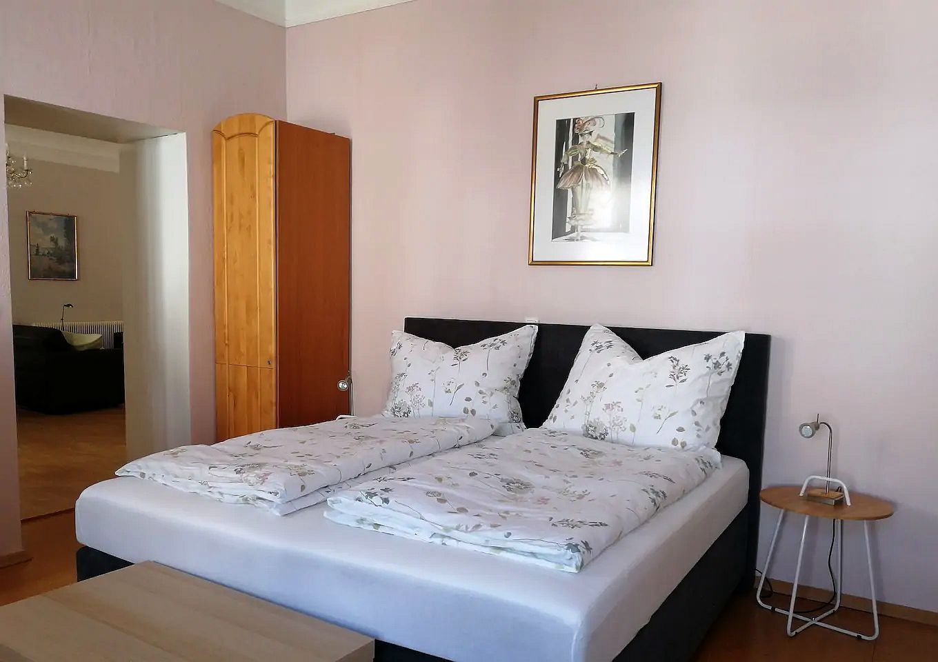 Schlafzimmer mit Doppelbett, Holzgarderobe und Wandbild.