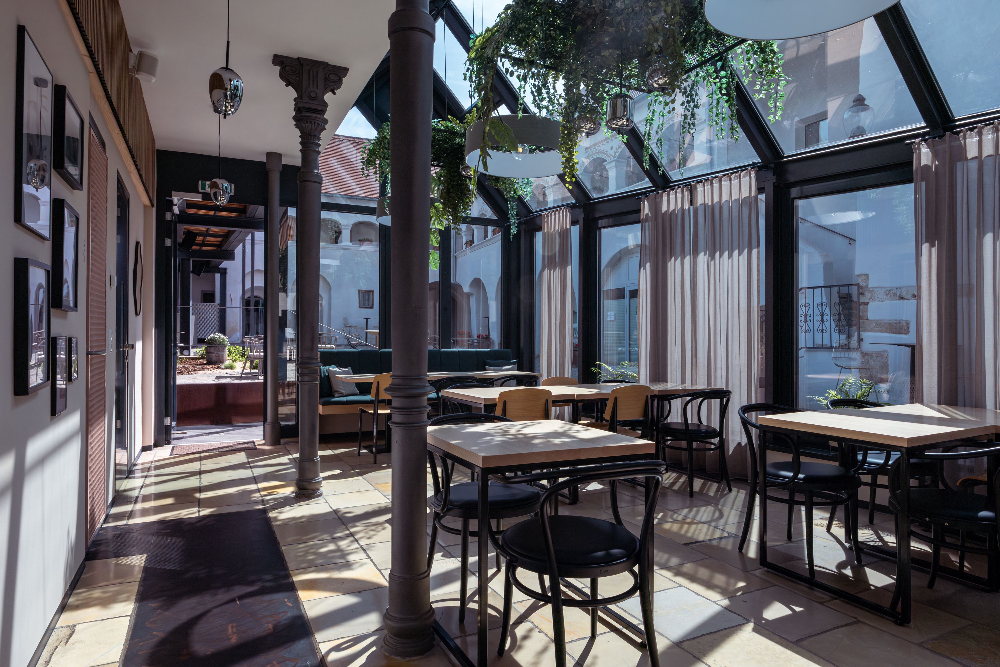 Innenansicht eines modernen Cafés mit Glasdach und Pflanzen.