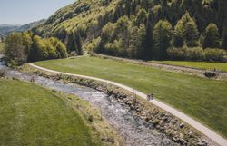 Zwei Radfahrerinnen fahren entlang des Radwegs neben einem Fluss.