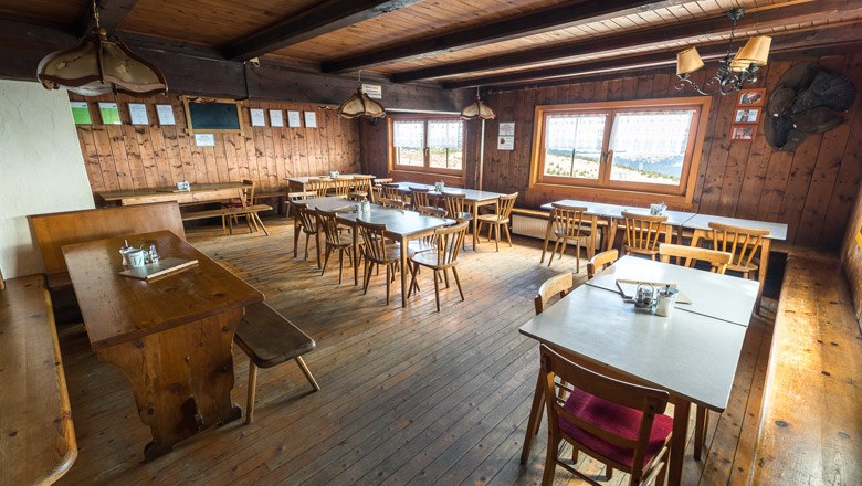 Gem&uuml;tliche Holzh&uuml;tte mit Tischen und St&uuml;hlen, rustikale Einrichtung.