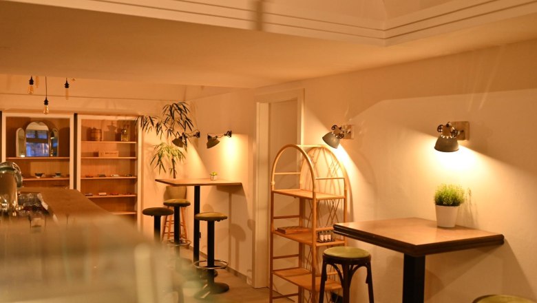 Innenansicht eines gem&uuml;tlichen Caf&eacute;s mit Holzm&ouml;beln und warmem Licht.