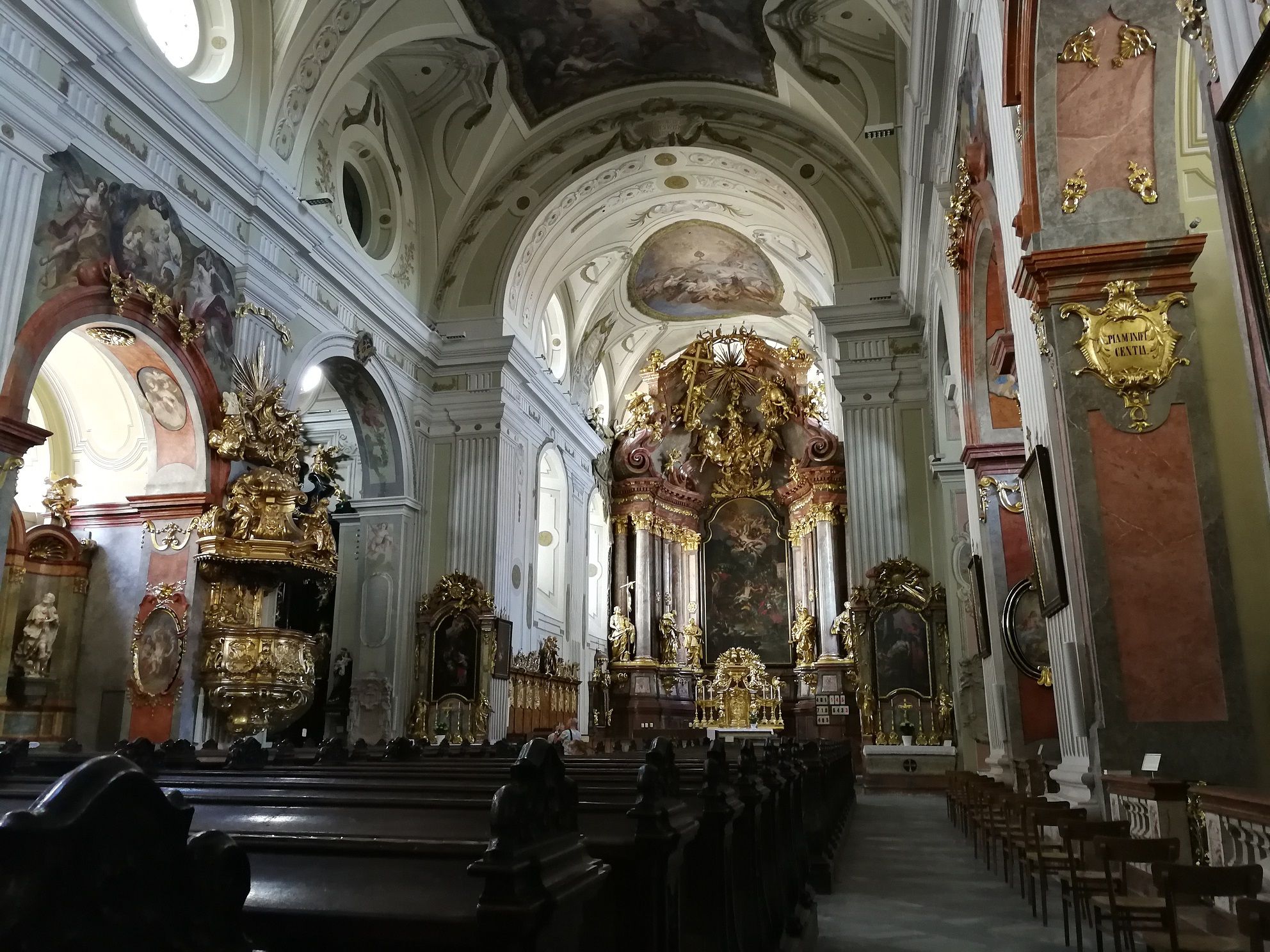 Innenansicht einer barocken Kirche mit reich verziertem Altar und Fresken.