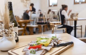 Heurigenjause, Weingläser im Hintergrund Menschen