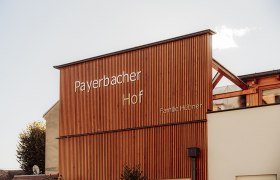 Holzfassade des Payerbacherhofs mit Schriftzug.