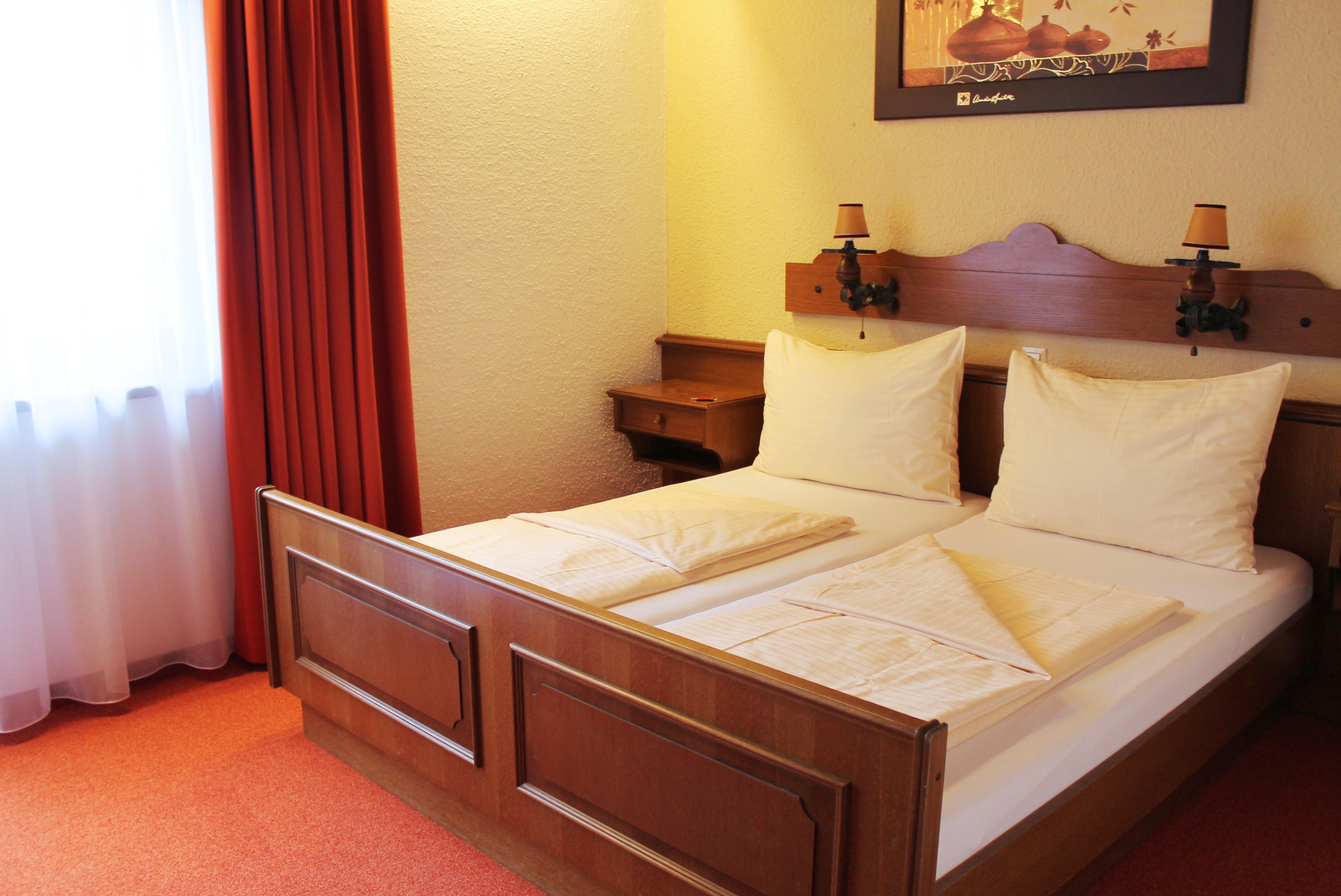 Ein gemütliches Hotelzimmer mit einem Doppelbett, roten Vorhängen und einem Bild an der Wand.