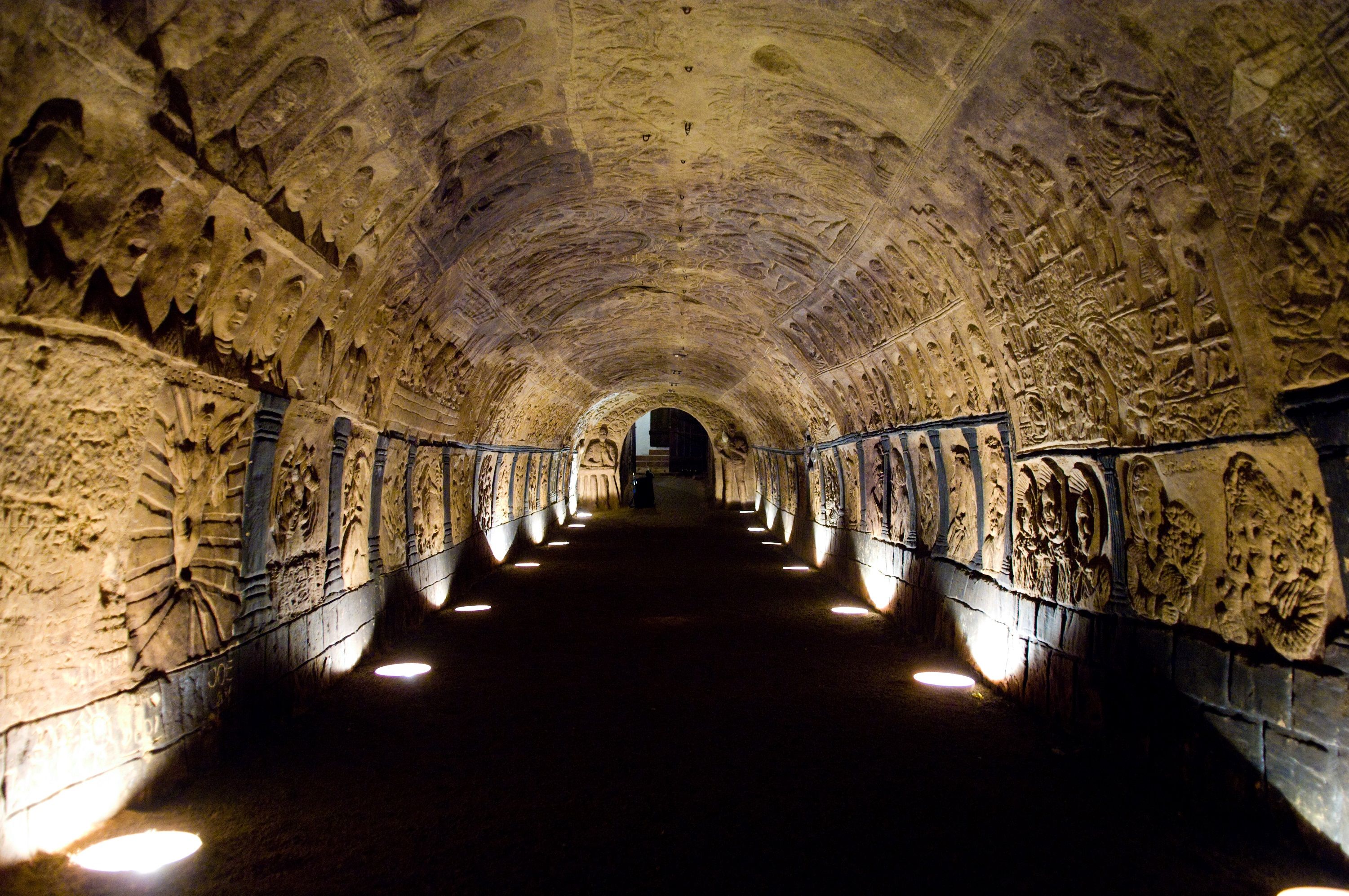 Ein beleuchteter Tunnel mit kunstvoll geschnitzten Wänden und Decken.