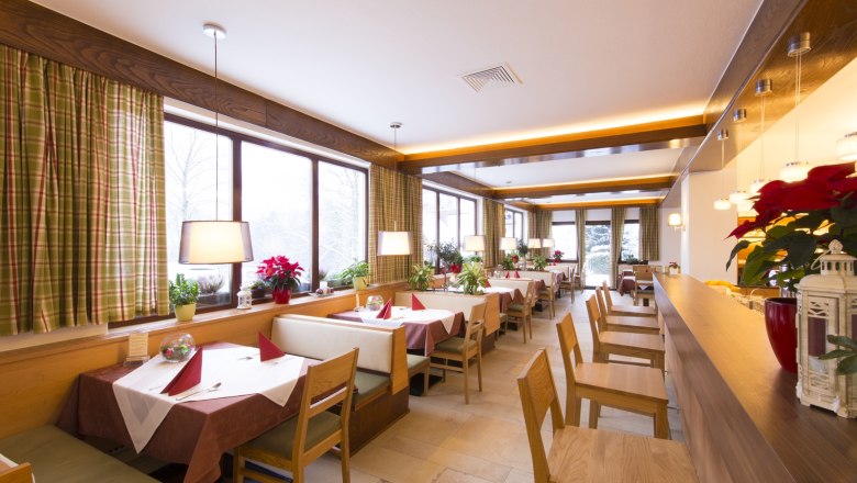 Innenansicht eines gemütlichen Restaurants mit Holzmöbeln und großen Fenstern.